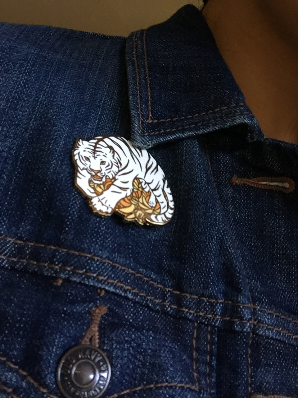Denim jacket with White Tiger pin attached.